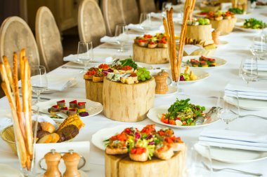 Servis masasında dilimlenmiş soğuk mezeler ve peynirli tabaklar.