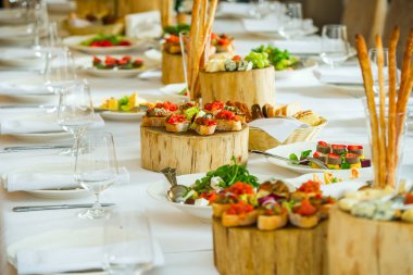 Tabaklarda soğuk mezeler ve servis masasında dilimlenmiş peynirle sabunlar.