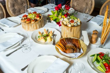 Servis masasında dilimlenmiş soğuk mezeler ve peynirli tabaklar.