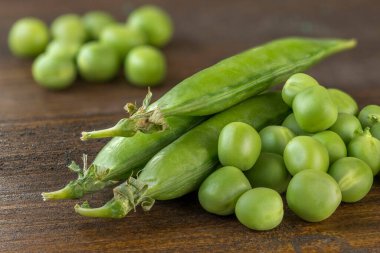Tahta bir masada arınmış bezelyelerle bezelye kabukları.