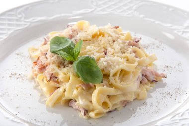 Peynirli Carbonara ve fesleğenle süslenmiş domuz pastırması.