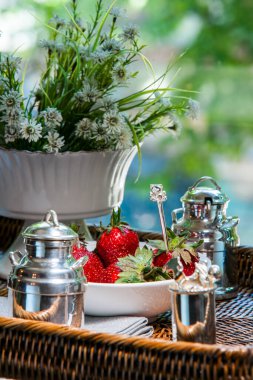 Çiçekler ve vazolarla dolu bir masada çilek.