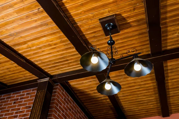 Outdoor metal chandelier under a wooden ceiling in a residential interior