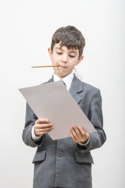 Ceketli çocuk ağzında bir kalem tutuyor ve elinde bir kurabiye tabakası tuttuğunu sanıyor.