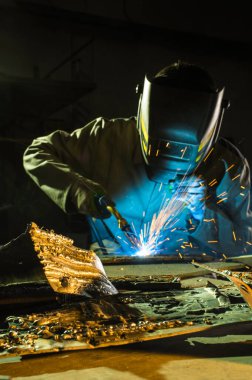 Argon kaynaklama, detaylar üzerinde çalışırken maske takan bir kaynakçı.