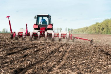 Kara toprak tarlasında tohum tohumu tarımsal sondajlarla dolu bir tarlada ekiciler.