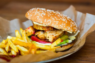 Tahta tabakta kızarmış patatesli tavuk burger.