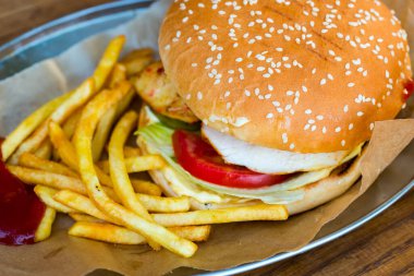 Susamlı hamburger ekmeği ve salatalı tavuk fileto ve kızarmış patates.