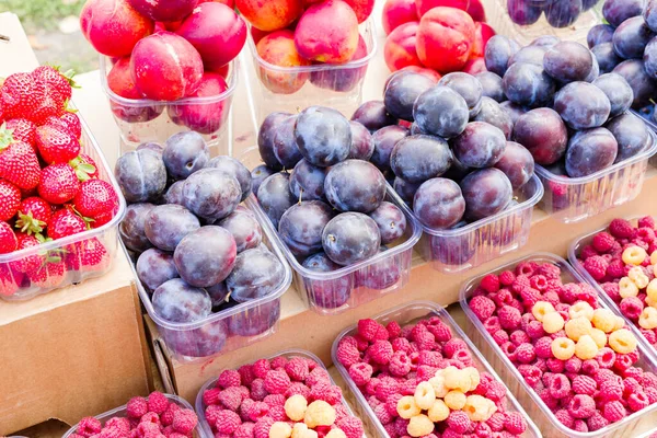 fresh fruit in boxes. plums and peaches and strawberries and raspberries in boxes on the counter