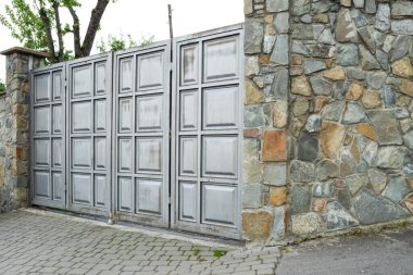 Kapısı ve taş çiti olan metal bir kapı.