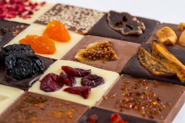 Süt, siyah ve beyaz çikolata, fındıklı ve kurutulmuş meyveler, farklı lezzetlerde.