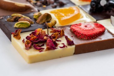 Süt, siyah ve beyaz çikolata, fındıklı ve kurutulmuş meyveler, farklı lezzetlerde.