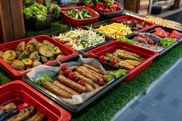 fried and baked street food for a quick snack in the fresh air, sausages, zucchini, salad, potatoes, fried potatoes, eggplant,