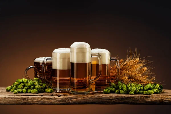 light beer in glasses with hops and wheat on a wooden board