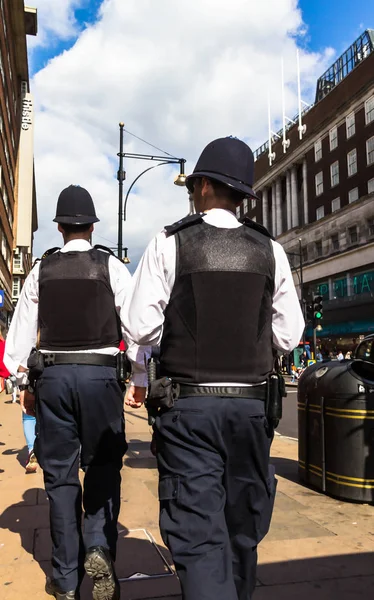 Londra, İngiltere - 9 Haziran 2015: Oxford Street. Şehirde devriye geleneksel üniformalı iki tanınmaz halde polis memuru.