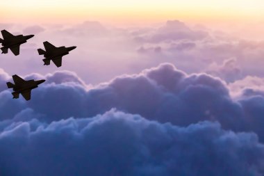 Günbatımı gökyüzü arka plan üzerinde üç F-35 uçaklarının siluetleri