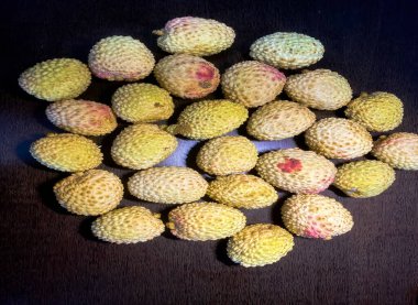 Lyche- küçük yuvarlak meyve tatlı beyaz kokulu et, büyük merkezi bir taş, ve ince kaba bir deri kahverengi ahşap masa üzerinde