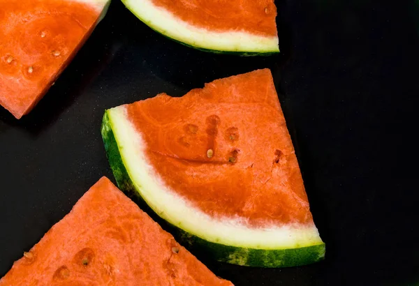 Slices of red ripe sweet watermelon on black background, closeup , selective focus