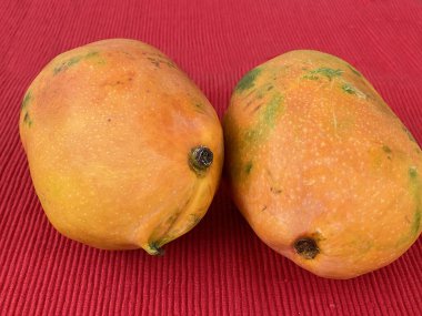 Masadaki kırmızı peçetede mango meyvesi.