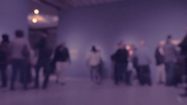 Sanat galerisi ziyareti sırasında yürüyen insanların görüntüsü. Kasıtlı olarak bulanık etki gösteren bir arka plan. 4K