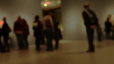 Sanat galerisi ziyareti sırasında yürüyen insanların görüntüsü. Kasıtlı olarak bulanık etki gösteren bir arka plan. 4K