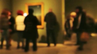 Sanat galerisi ziyareti sırasında yürüyen insanların görüntüsü. Kasıtlı olarak bulanık etki gösteren bir arka plan. 4K