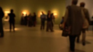 Sanat galerisi ziyareti sırasında yürüyen insanların görüntüsü. Kasıtlı olarak bulanık etki gösteren bir arka plan. 4K