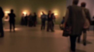 Sanat galerisi ziyareti sırasında yürüyen insanların görüntüsü. Kasıtlı olarak bulanık etki gösteren bir arka plan. 4K