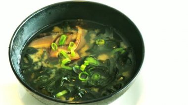 Büyük siyah kasede Miso çorbası. Geleneksel Japon yemeğidir. Ana malzemeler miso macunu, tofu, wakame deniz yosunu ve shiitake mantarlarıdır. 4K