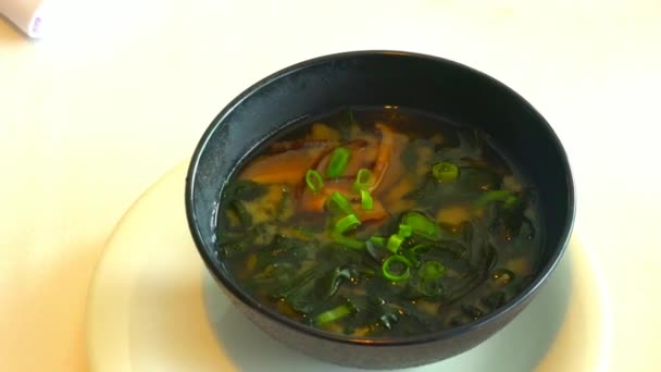 Miso soup in the big black bowl. It is traditional japanese food. Main ingredients are miso paste, tofu, wakame seaweed and shiitake mushrooms. 4K — Stock Footage Miso Soup Big Black Bowl Traditional Japanese Food Main Ingredients Royalty Free Stock Footage
