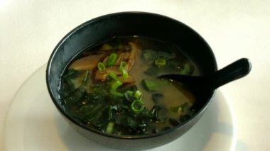 Büyük siyah kasede Miso çorbası. Geleneksel Japon yemeğidir. Ana malzemeler miso macunu, tofu, wakame deniz yosunu ve shiitake mantarlarıdır. 4K