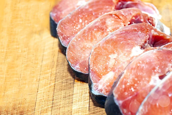 Appetizing pieces, slices of red fish lie on an old cut cutting Board. Pickled fish steaks shot with shallow depth of field, natural light natural color — Stock Image Appetizing Pieces Slices Red Fish Lie Old Cut Cutting Board Royalty Free Stock Images