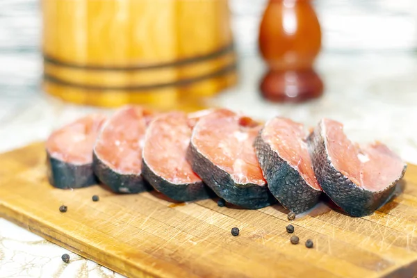 Appetizing pieces, slices of red fish lie on an old cut cutting Board. Pickled fish steaks shot with shallow depth of field, natural light natural color — Stock Image Appetizing Pieces Slices Red Fish Lie Old Cut Cutting Board Royalty Free Stock Photos