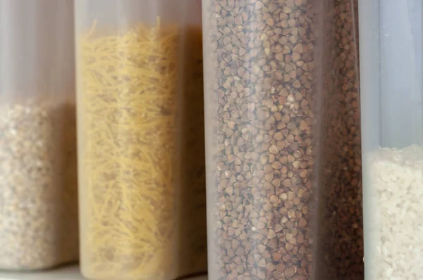 White plastic storage containers with various cereals and pasta close up