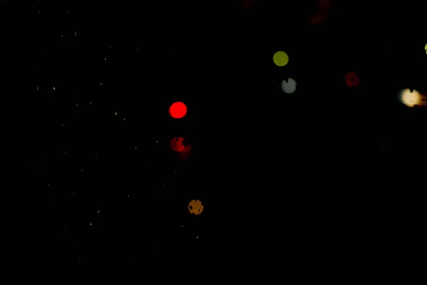 defocused round bokeh of city street lights, headlights of passing cars at night. Multi-colored bokeh on a black background.
