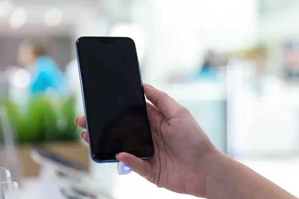 New mobile smartphone shown in girl\'s hand with empty black screen, on isolated background