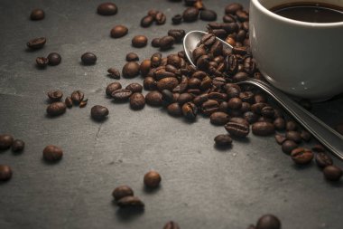 Kahve çekirdekleri ile kaşık ve kahve Kupası gri bir arka plan