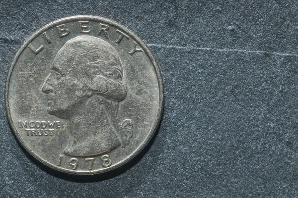 A quarter dollar on a rock table