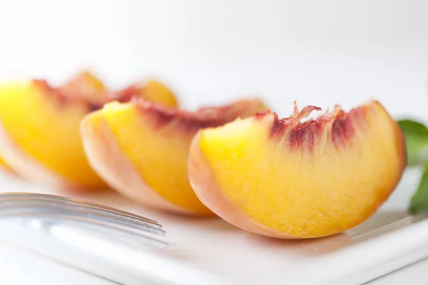 Slices of peach served on a white ceramic plate