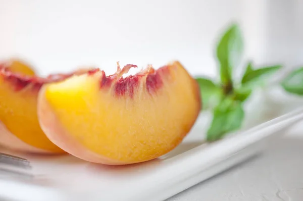 Slices of peach served on a white ceramic plate