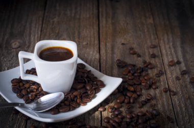 Kare bir fincan kahve duman ile eski ahşap masa üzerinde bazı bir kaşık kuru fasulye