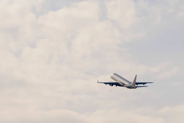 En airplan går mot molnen vid solnedgången efter take off — Stockfoto