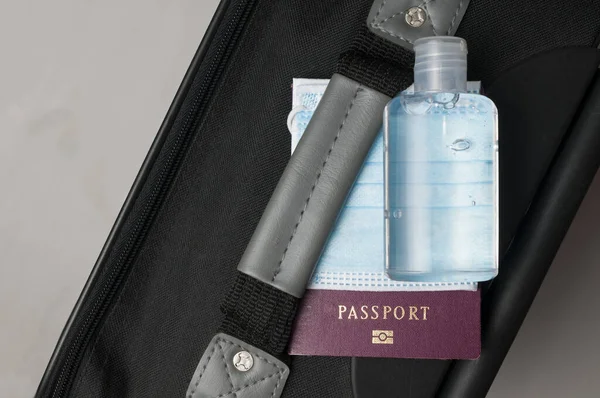Hand luggage for air travel with surgical mask, sanitizing gel and passport. The use of the mask on the plane will be mandatory to limit infections by covid-19