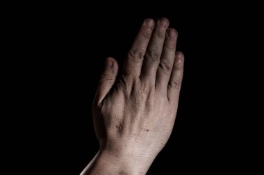 Siyah arka planda beyaz bir adamın dua eden elleri.