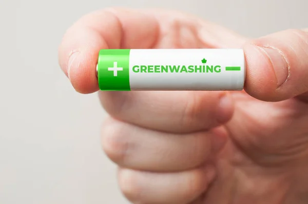 Hombre Sostiene Una Batería Verde Blanca Con Palabra Greenwashing Impresa — Foto de Stock