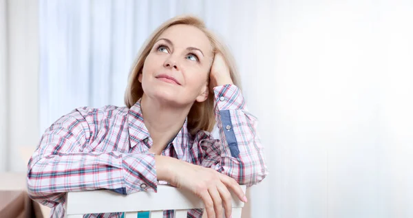 Attraktive Frau mittleren Alters, die zu Hause entspannt in die Kamera blickt. das schöne Gesicht aus nächster Nähe. — Stockfoto