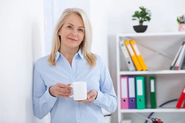 Ler mitten åldern affärsman med en kopp kaffe på kontoret. Fika. — Stockfoto