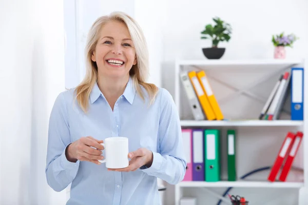 Ler mitten åldern affärsman med en kopp kaffe på kontoret. Fika. — Stockfoto