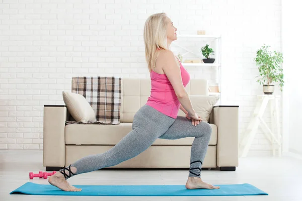 Mujer de mediana edad en sus 50 años estirándose para hacer ejercicio —  Fotos de Stock