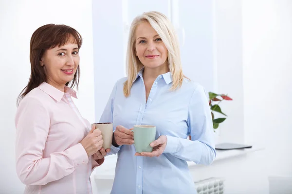 Office coffee break. Two female colleagues with cups of coffee talking. — Stock Photo, Image